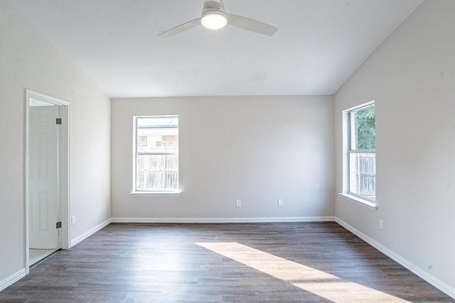 empty room with a wealth of natural light, ceiling fan, dark wood-type flooring, and vaulted ceiling