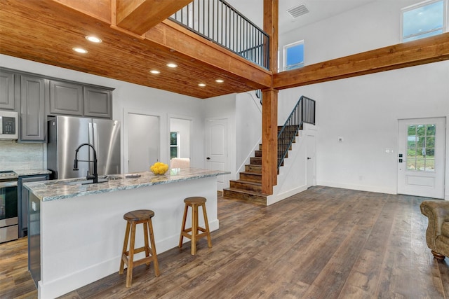 kitchen with gray cabinetry, a center island with sink, sink, and appliances with stainless steel finishes