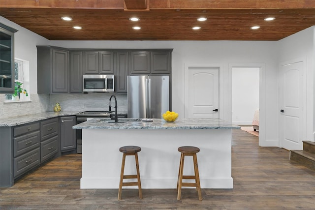 kitchen featuring gray cabinetry, light stone counters, a center island, and stainless steel appliances