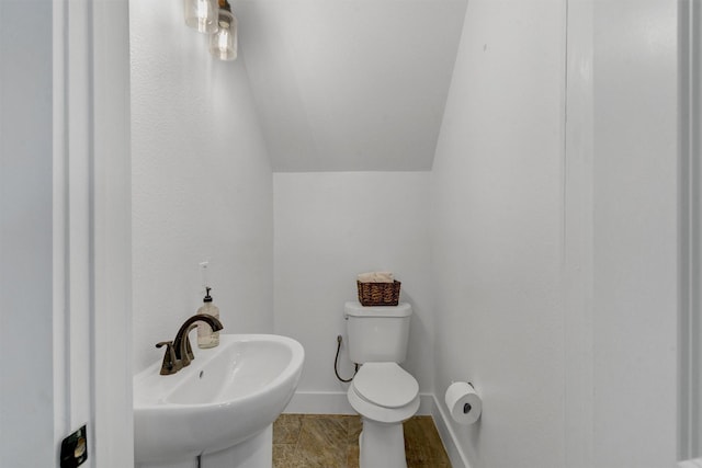 bathroom featuring sink, vaulted ceiling, and toilet