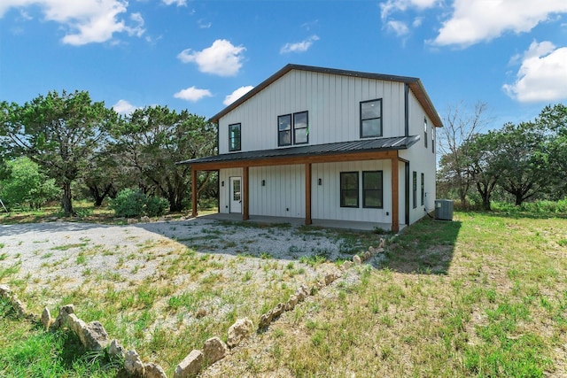 rear view of property with a lawn and central air condition unit