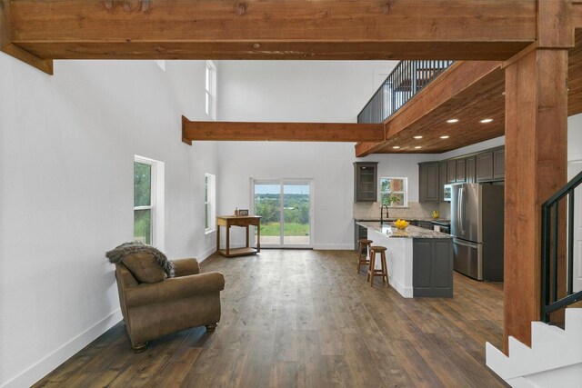 interior space featuring decorative backsplash, stainless steel fridge, dark hardwood / wood-style flooring, a breakfast bar, and a center island