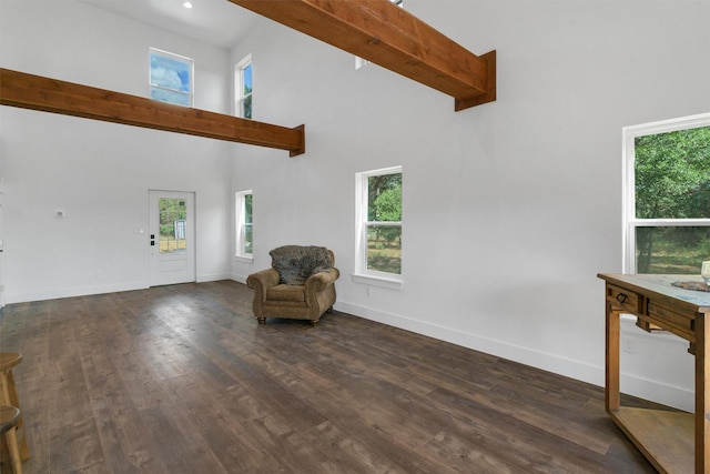 unfurnished room featuring beam ceiling, a towering ceiling, and dark hardwood / wood-style floors