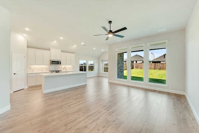 unfurnished living room featuring ceiling fan, light hardwood / wood-style flooring, sink, and lofted ceiling