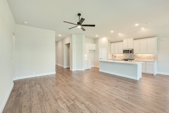 kitchen featuring a center island with sink, ceiling fan, light hardwood / wood-style floors, and white cabinets