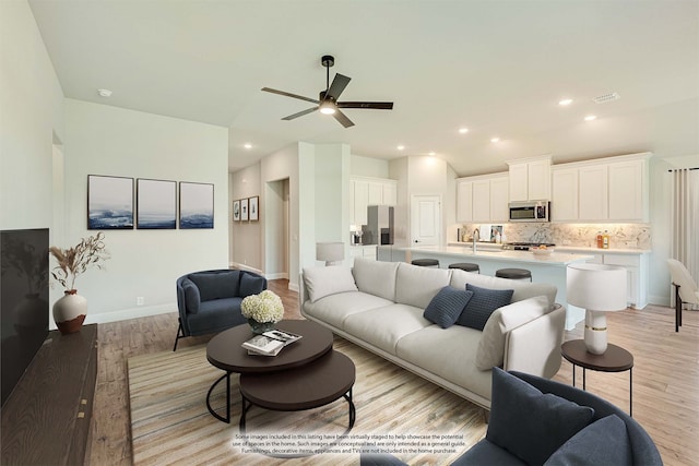 living room featuring ceiling fan, sink, and light hardwood / wood-style flooring