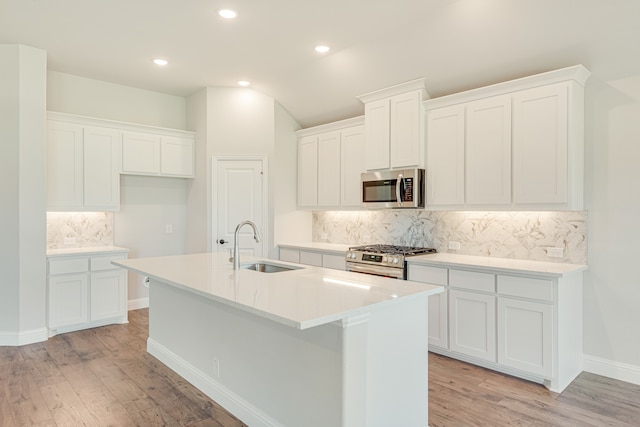 kitchen featuring white cabinets, backsplash, light hardwood / wood-style flooring, and appliances with stainless steel finishes