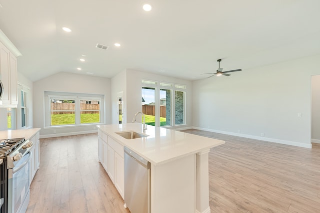 kitchen with sink, gas range gas stove, light hardwood / wood-style floors, stainless steel dishwasher, and a kitchen island with sink