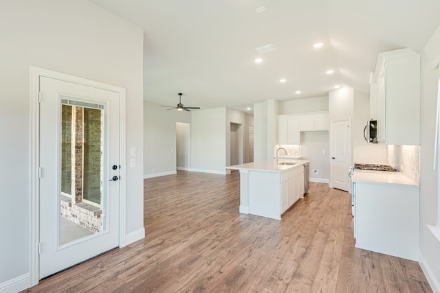 kitchen featuring sink, light hardwood / wood-style floors, a center island with sink, and white cabinets