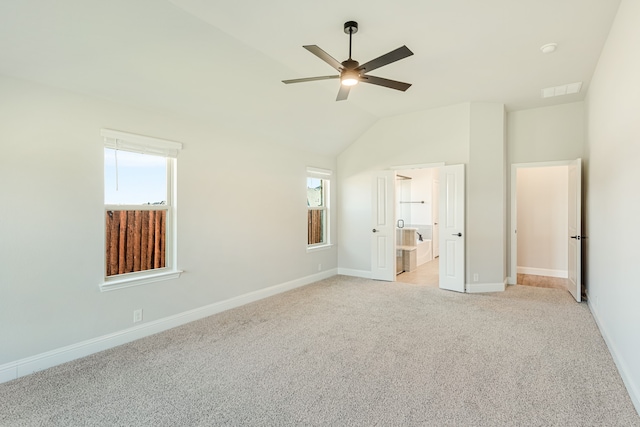 unfurnished bedroom featuring ceiling fan, vaulted ceiling, light colored carpet, and multiple windows