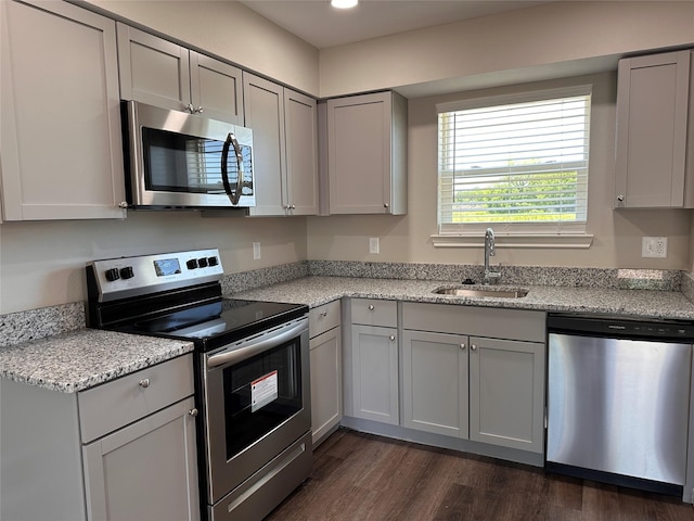 kitchen featuring dark hardwood / wood-style floors, sink, stainless steel appliances, and light stone counters