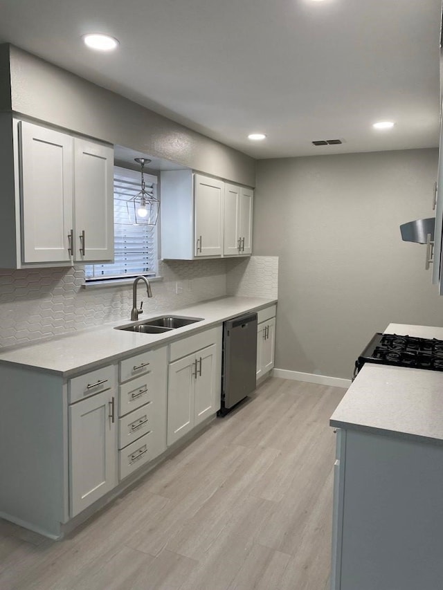 kitchen featuring backsplash, sink, stainless steel dishwasher, and light wood-type flooring