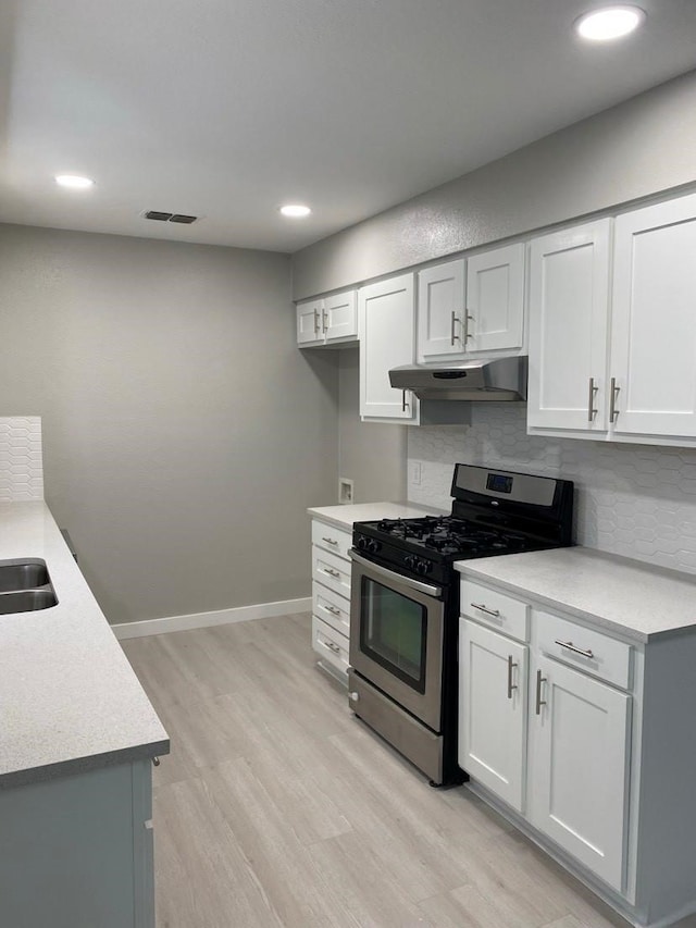 kitchen featuring stainless steel gas range oven, light hardwood / wood-style floors, backsplash, and white cabinetry