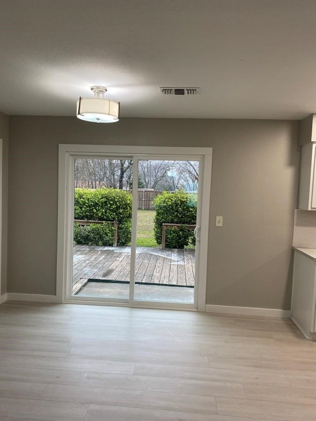 doorway with a healthy amount of sunlight and light hardwood / wood-style flooring