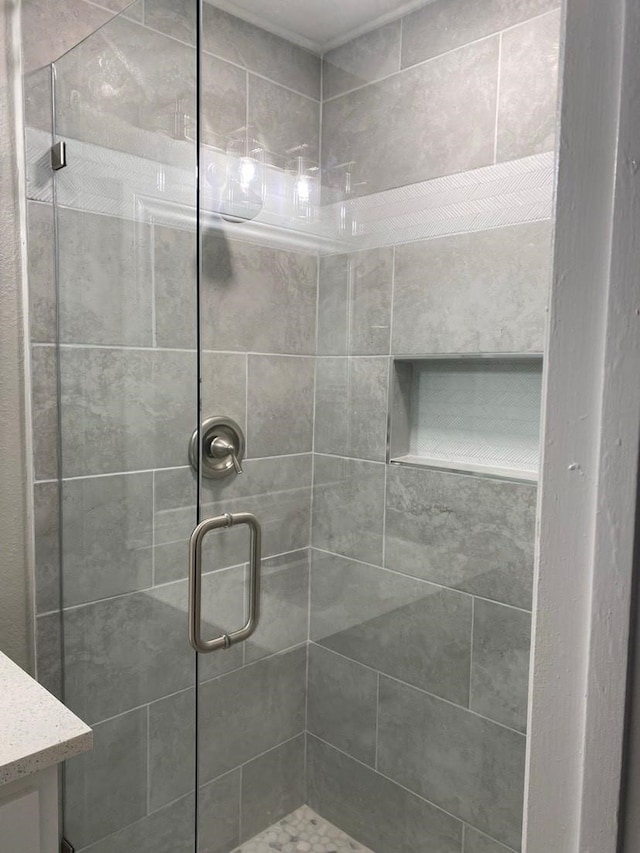 bathroom featuring a shower with shower door and vanity