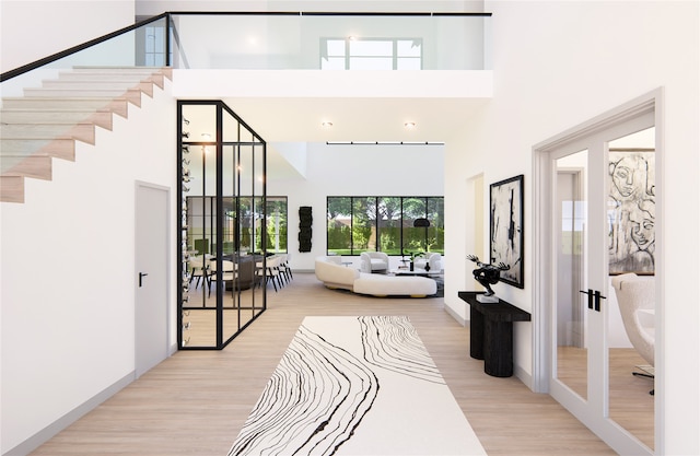 foyer with light wood-type flooring, french doors, and a towering ceiling