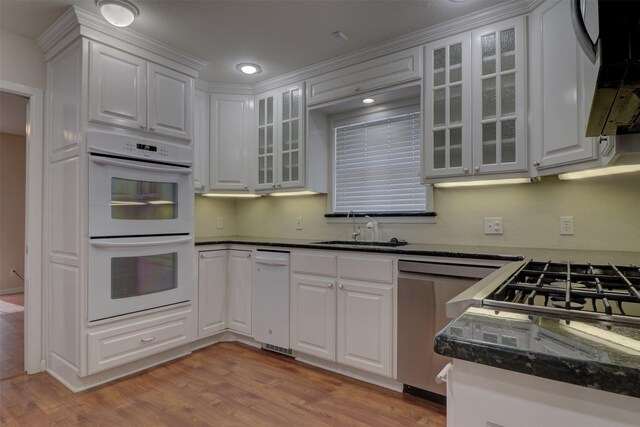 kitchen with light wood-type flooring, sink, white cabinets, white double oven, and stainless steel dishwasher