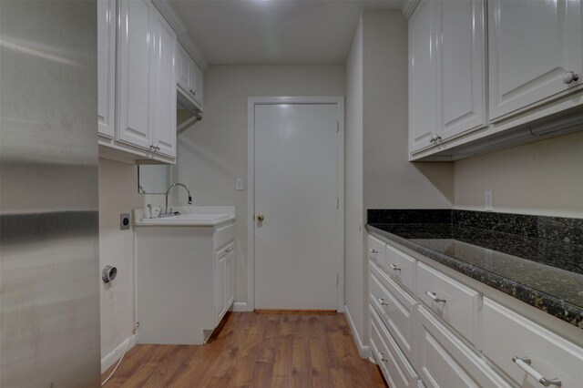 kitchen featuring sink, dark stone counters, hardwood / wood-style floors, and white cabinetry