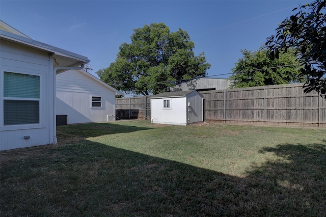 view of yard featuring a fenced backyard, a storage unit, and an outbuilding