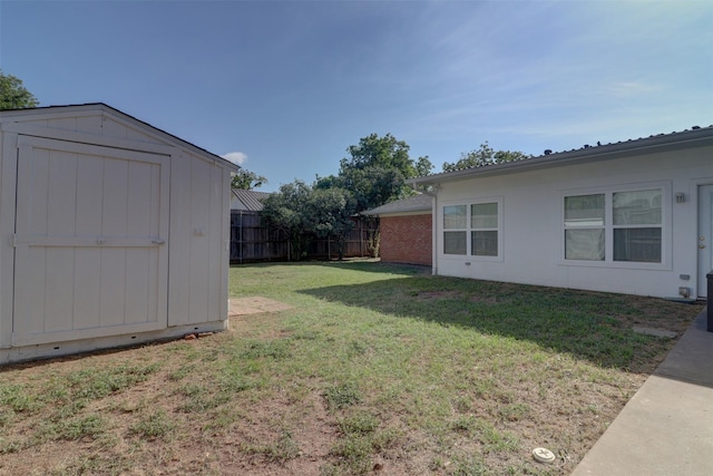 view of yard with a storage shed, fence, and an outbuilding