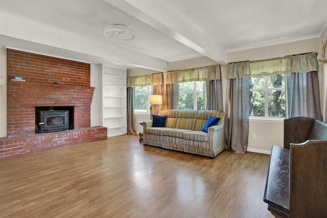 living room with beamed ceiling, light hardwood / wood-style floors, a wood stove, and a wealth of natural light