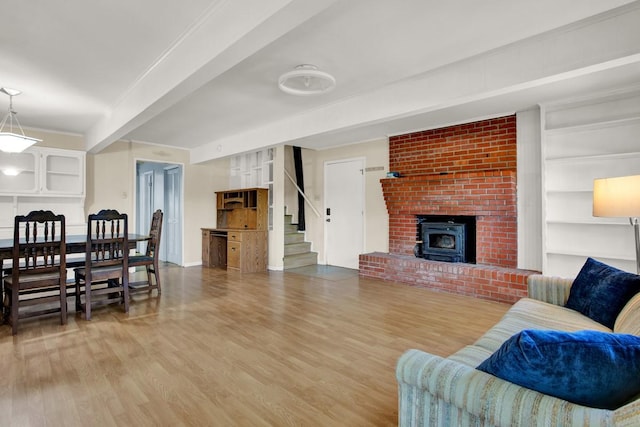 living room featuring a wood stove, built in features, beamed ceiling, wood-type flooring, and ornamental molding