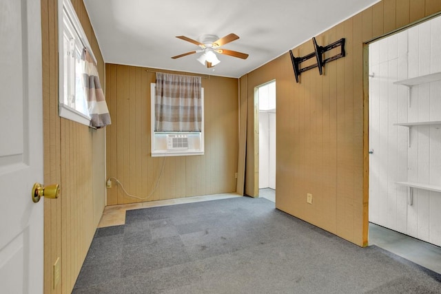 carpeted spare room featuring ceiling fan and wooden walls