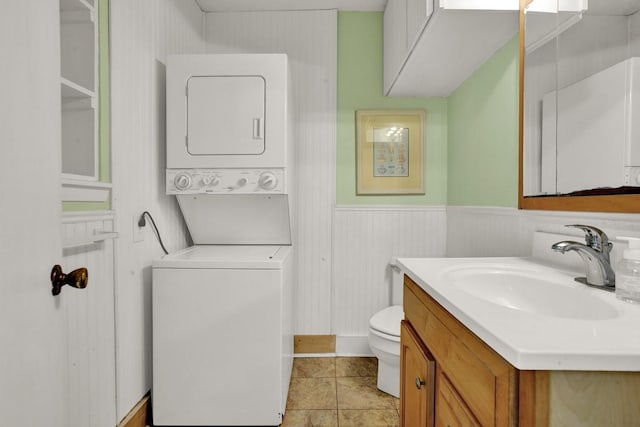 bathroom featuring tile patterned floors, vanity, stacked washing maching and dryer, and toilet