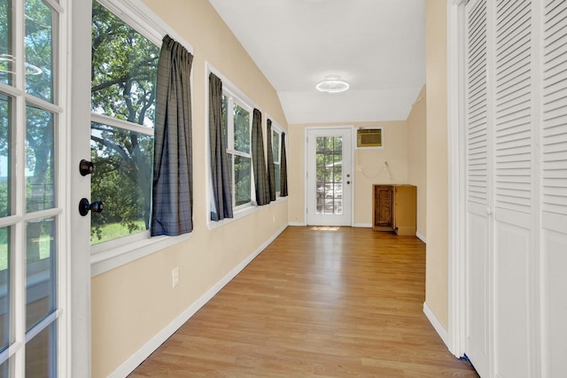 hallway featuring light hardwood / wood-style flooring, vaulted ceiling, and a wall unit AC