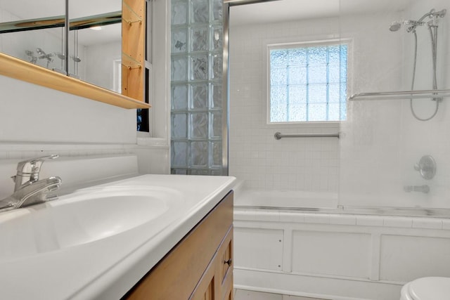 full bathroom with combined bath / shower with glass door, vanity, and toilet