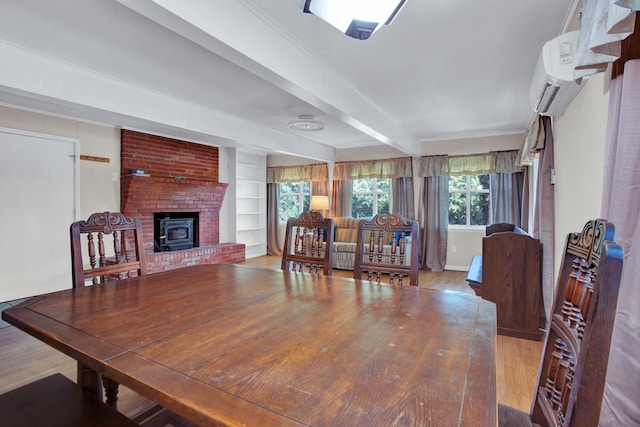 dining space featuring built in shelves, a wall mounted AC, beam ceiling, hardwood / wood-style floors, and a wood stove