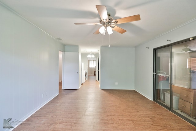 spare room featuring crown molding, light hardwood / wood-style floors, and ceiling fan with notable chandelier