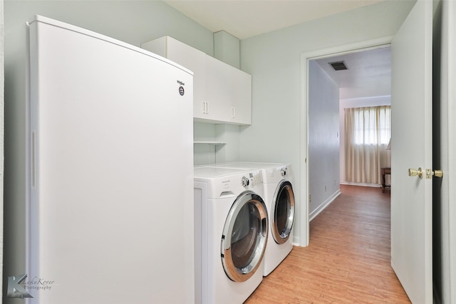 laundry room with washer and dryer, cabinets, and light hardwood / wood-style flooring