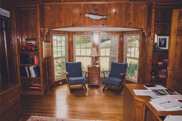 living area with wood-type flooring and wood walls