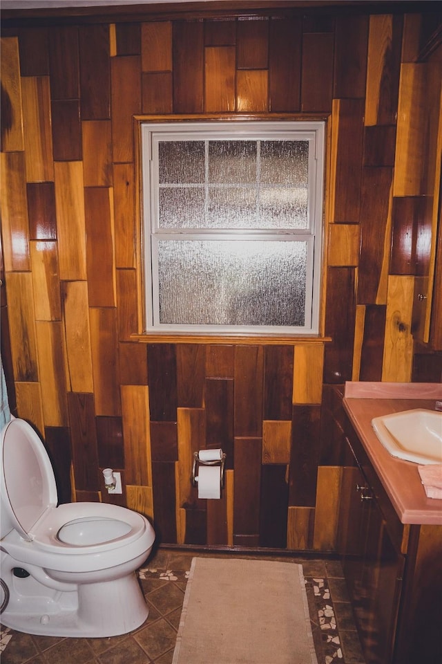 bathroom featuring toilet, wooden walls, tile patterned flooring, and vanity