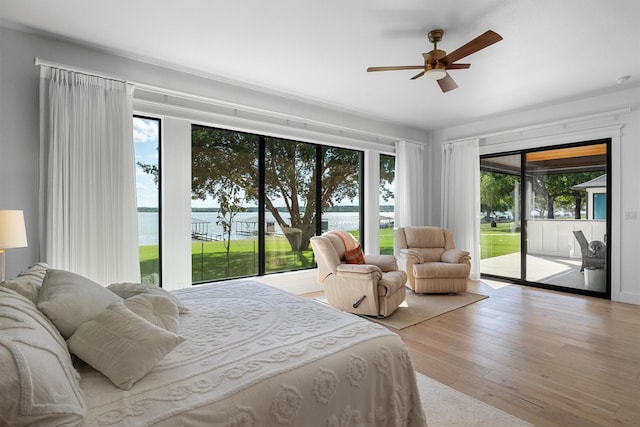 bedroom with multiple windows, a water view, access to exterior, and ceiling fan