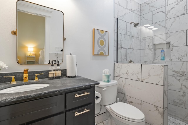 bathroom with vanity, tiled shower, and toilet