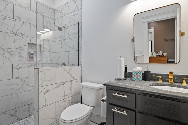 bathroom featuring a tile shower, vanity, and toilet