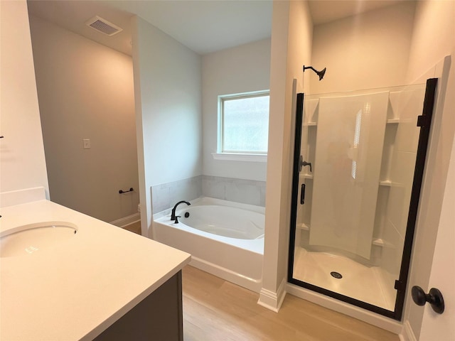 bathroom with a stall shower, visible vents, wood finished floors, and a garden tub
