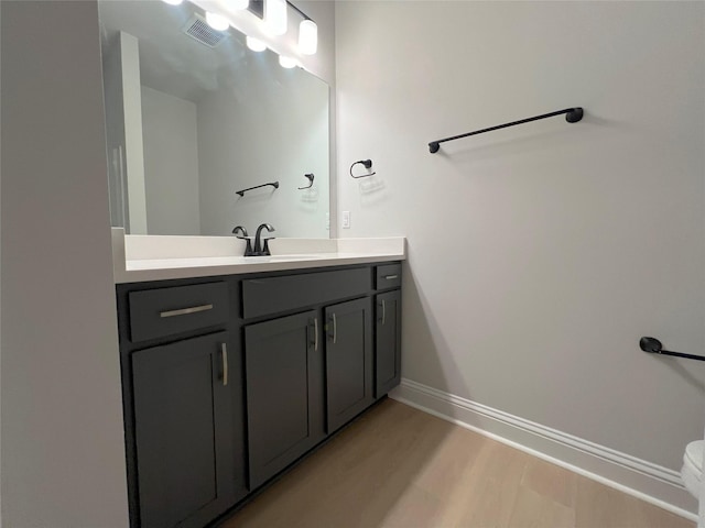 bathroom featuring baseboards, visible vents, wood finished floors, and vanity