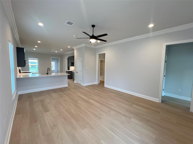 unfurnished living room with a sink, light wood-style flooring, baseboards, visible vents, and ceiling fan