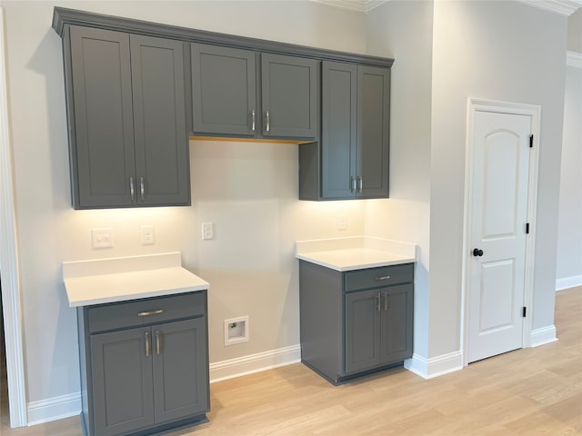 kitchen featuring crown molding, light hardwood / wood-style flooring, and gray cabinetry