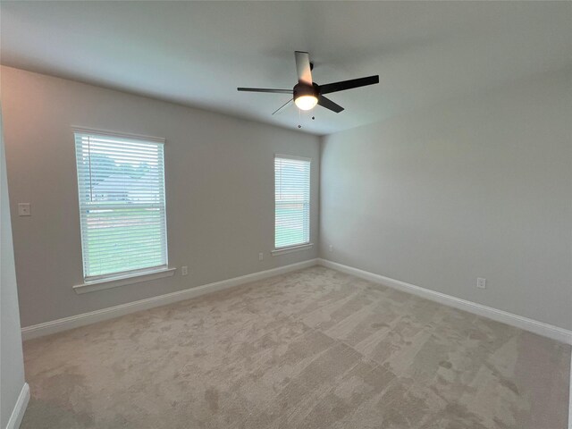 empty room with baseboards, ceiling fan, and light colored carpet