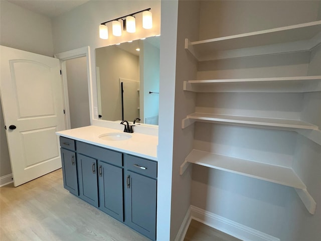 bathroom featuring baseboards, wood finished floors, and vanity