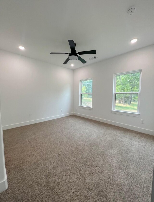 carpeted spare room with ceiling fan