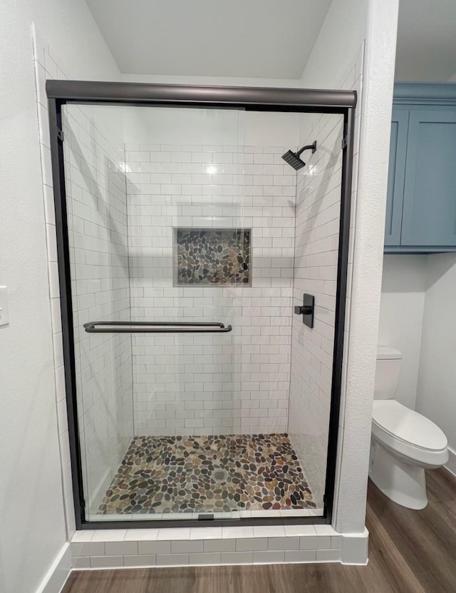 bathroom featuring hardwood / wood-style flooring, toilet, and a shower with door