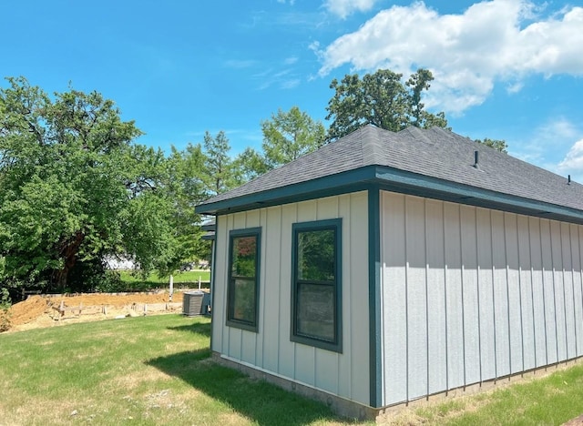 view of outdoor structure with central AC and a yard