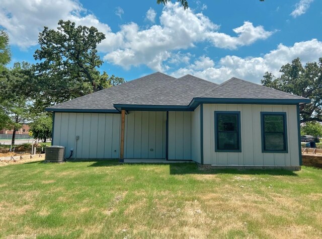 rear view of property featuring cooling unit and a lawn