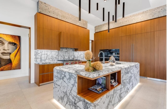 kitchen featuring tasteful backsplash, stove, stainless steel gas stovetop, a kitchen island with sink, and a high ceiling