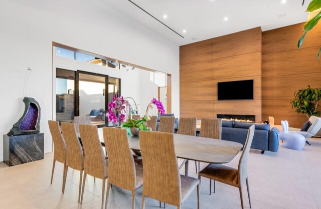 dining area featuring a large fireplace, a high ceiling, and wooden walls